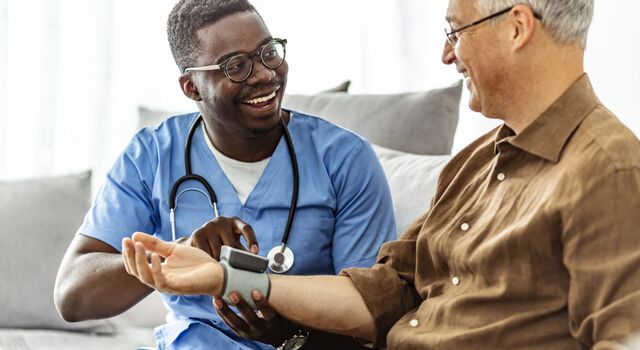 COLOUR-IMAGE_black-male-nurse-taking-pulse-of-patient-smiling_apr26