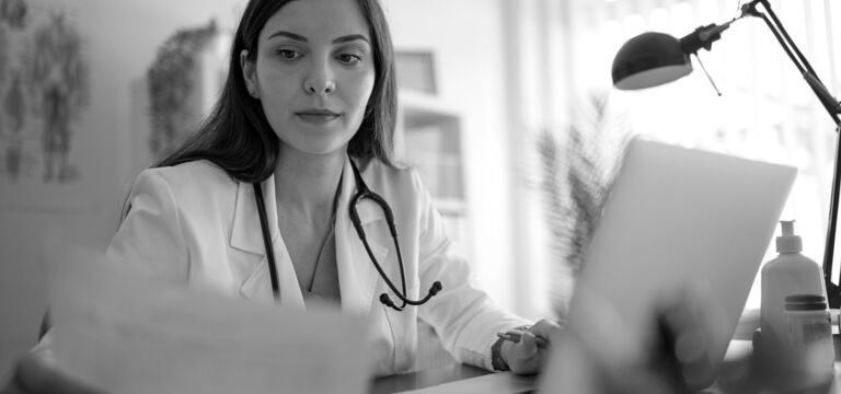 SINGLE-IMAGE_doctor-checking-paperwork-and-laptop_aug25