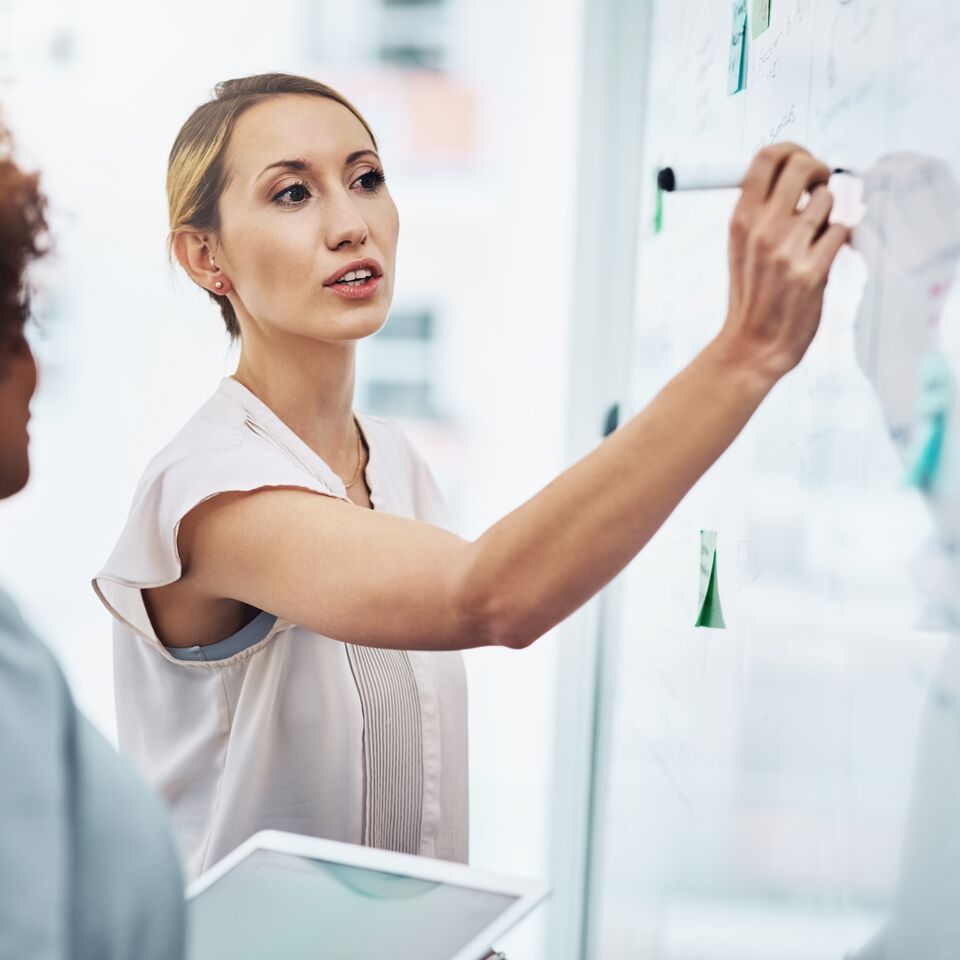 COLOUR-IMAGE_woman-writing-on-white-board_jul26