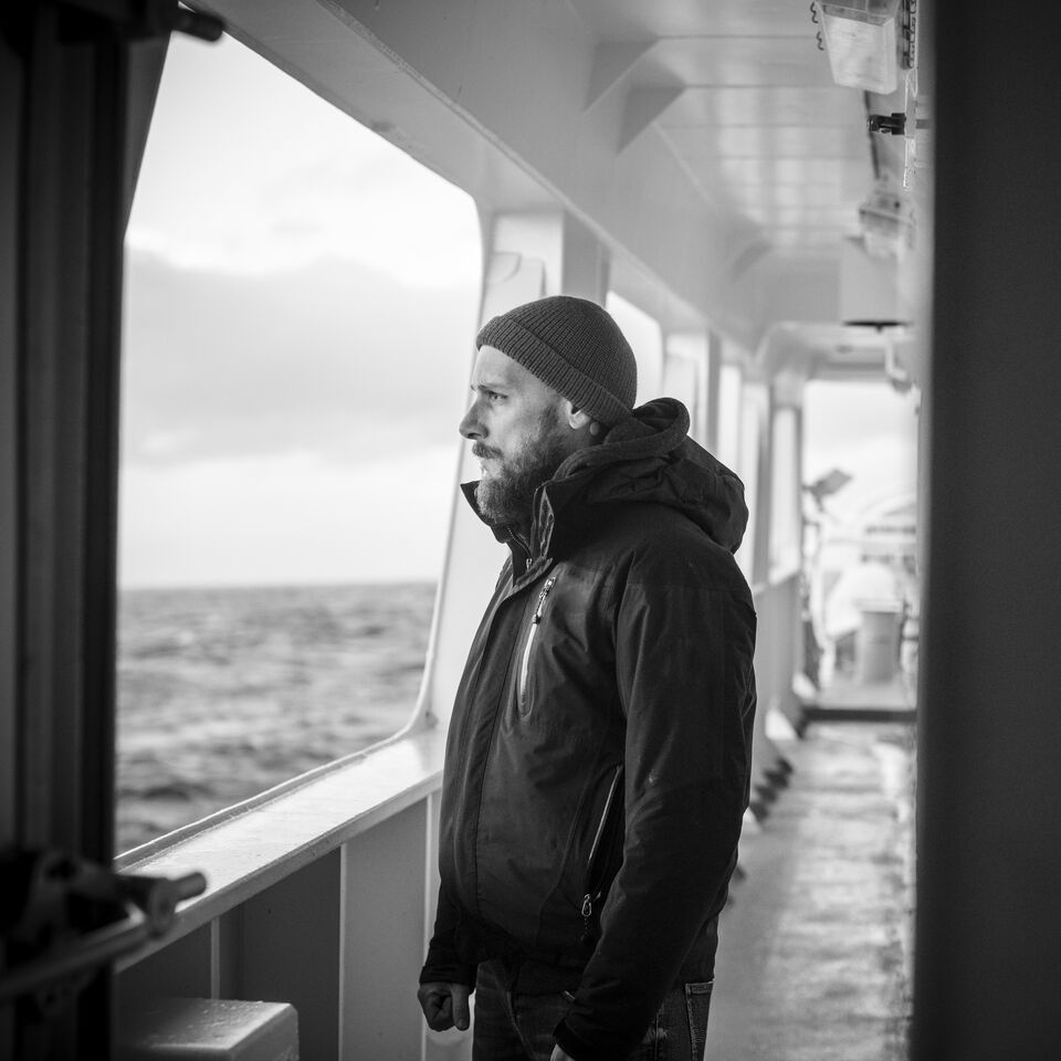 SINGLE-IMAGE_man-with-beanie-hat-on-boat-looking-to-sea-black-and-white_jul24